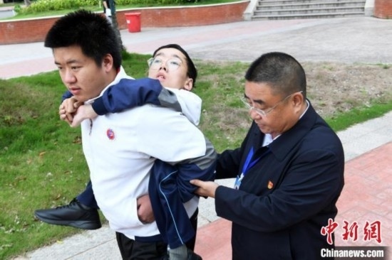 朱金祥背著鐘華強(qiáng)去教室上課的路上，也經(jīng)常碰到值班的校領(lǐng)導(dǎo)和老師前來搭把手。 卓忠偉 攝