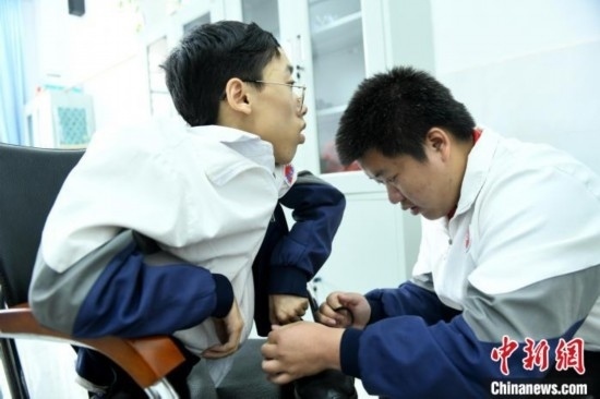 江西省南康中學(xué)北校區(qū)的高三學(xué)生朱金祥(右)正在給鐘華強(qiáng)(左)系好鞋帶。 卓忠偉 攝