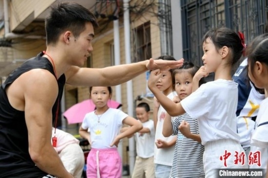 圖為大學(xué)生志愿者在組織孩子們參加體育健身活動(dòng)。廖光福 攝