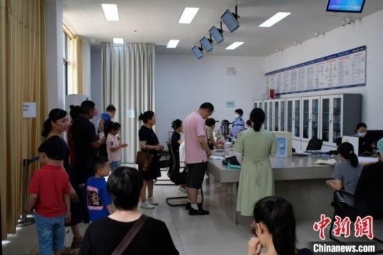 圖為在戶籍辦證廳內(nèi)排隊等待的家長和孩子。劉俊聰 攝