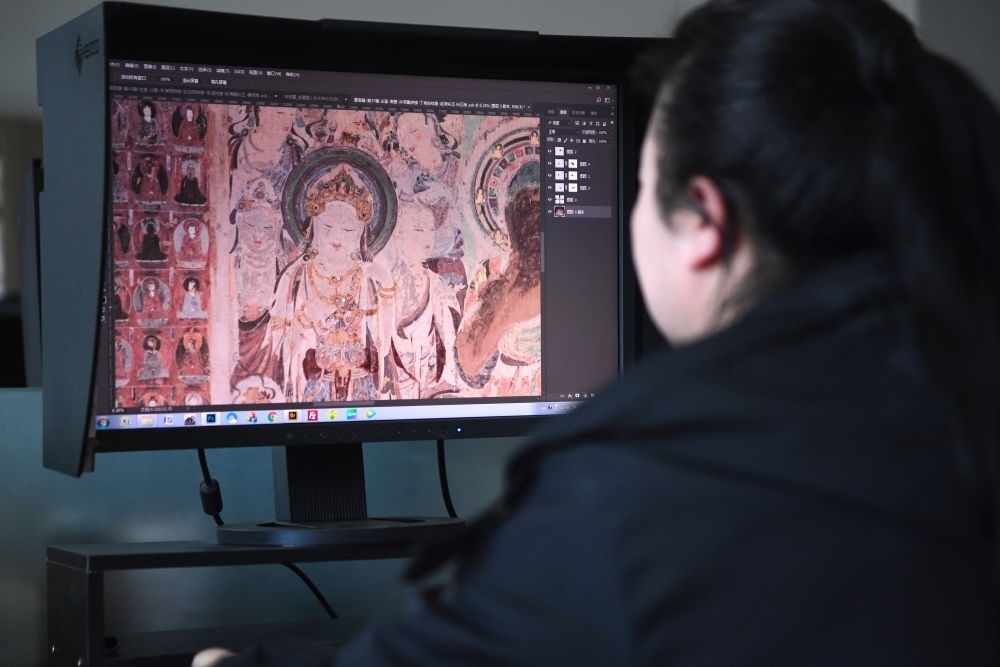 敦煌研究院文物數字化保護團隊圖像處理人員年海麗在拼接壁畫圖像（2023年4月25日攝）。數字化探索為莫高窟的保護與傳承開辟了全新路徑，數字技術讓敦煌文物走出洞窟，跨出國門，走向“永久保存、永續(xù)利用”。新華社記者 陳斌 攝