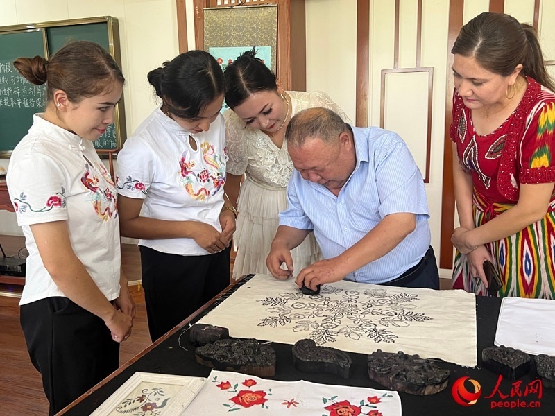 國(guó)家級(jí)非物質(zhì)文化遺產(chǎn)模戳印花布技藝傳承人吾吉阿西木?吾舒爾展示模戳印花布的制作過(guò)程。人民網(wǎng)記者 常雪梅攝