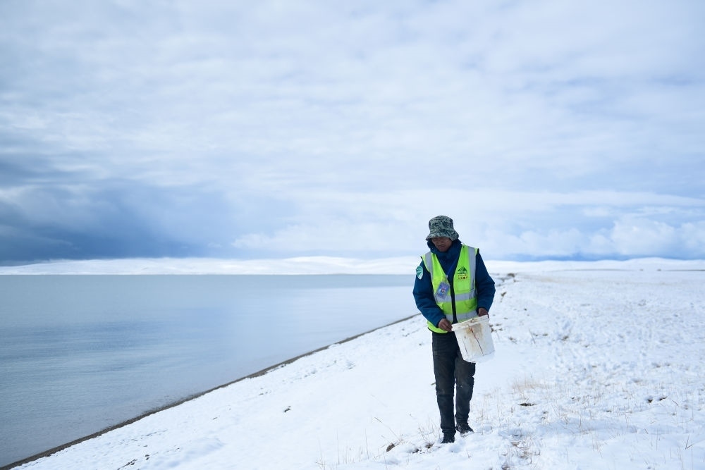 2021年10月20日，在青海省果洛藏族自治州瑪多縣扎陵湖鄉(xiāng)勒那村，三江源國家公園黃河源園區(qū)生態(tài)管護員在扎陵湖邊撿拾垃圾。新華社記者 張龍 攝