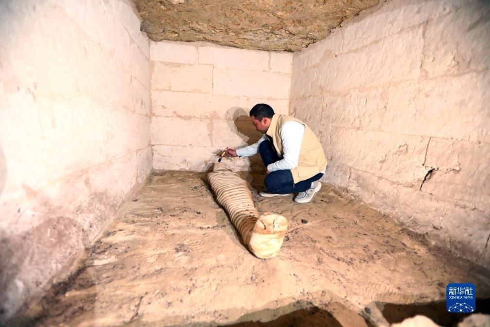 10月15日，在埃及明亞省考古現(xiàn)場，考古人員清理一座石鑿墓中的木乃伊。新華社發(fā)（艾哈邁德·戈馬攝）