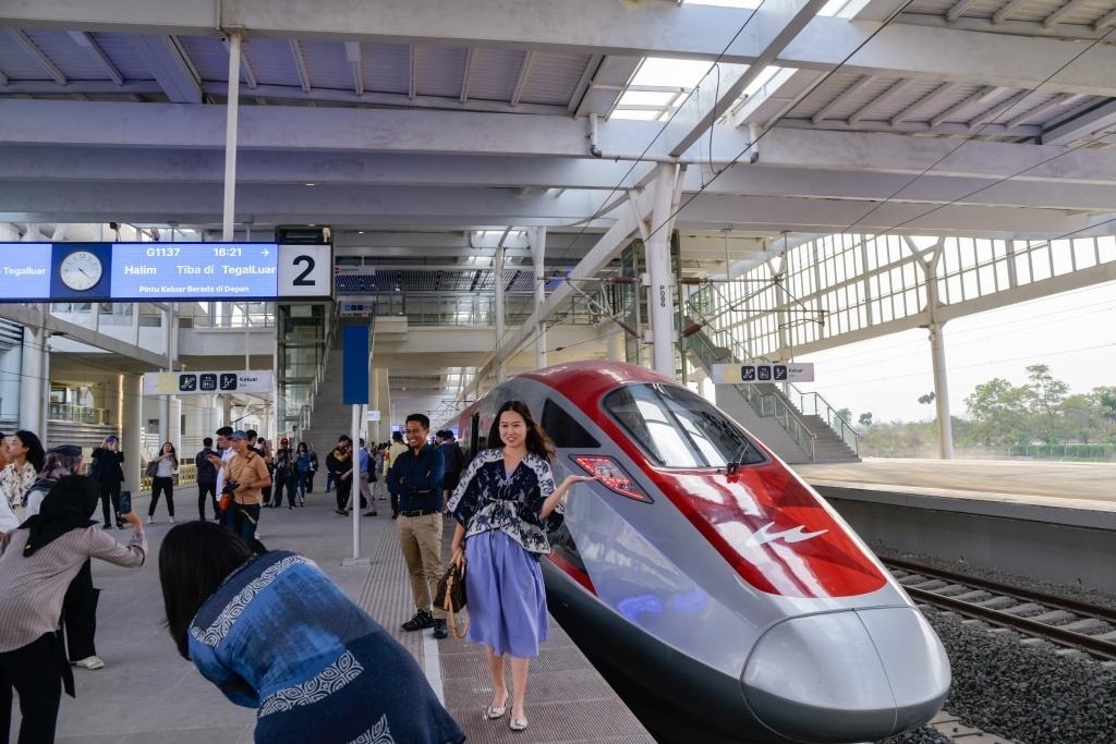 10月17日，在印度尼西亞萬隆德卡魯爾站，乘客在站臺上和雅萬高鐵高速動車組列車合影。