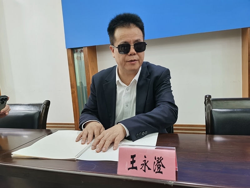 全國(guó)人大代表王永澄正在閱讀盲文版代表建議答復(fù)。本報(bào)記者 張 璁?dāng)z