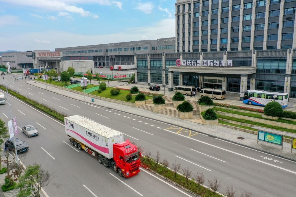 2023年10月11日，滿載筆記本電腦配件、發(fā)電機組件等產(chǎn)品的西部陸海新通道跨境公路班車從重慶南彭公路保稅物流中心駛出，將途經(jīng)廣西憑祥，直達越南（無人機照片）。新華社記者 黃偉 攝