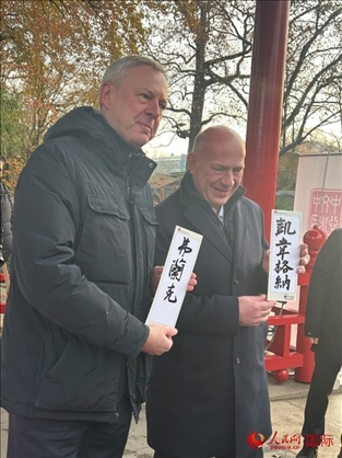 柏林市長韋格納（右）、動物園監(jiān)事會主席布魯克曼（左）手持中國文化中心工作人員現(xiàn)場手書的中文名字。人民網(wǎng)記者 徐馨攝