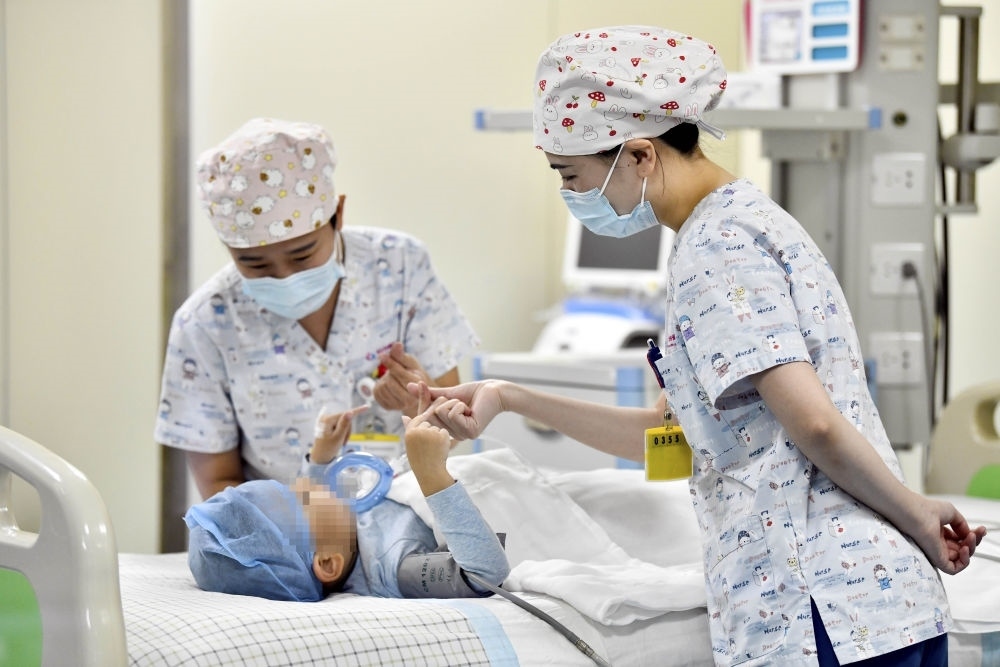 在山東省棗莊市婦幼保健院兒童ICU病房，醫(yī)護人員為完成靶向治療藥物諾西那生鈉的4歲脊髓性肌萎縮癥患兒加油鼓勁（2022年1月1日攝）。諾西那生鈉注射液是我國首個獲批治療脊髓性肌萎縮癥的進口藥物，2019年進入中國市場時，每針價格近70萬元。在2021年國家醫(yī)保目錄藥品談判中，以3.3萬元每針的價格進入新版醫(yī)保藥品目錄。新華社記者 郭緒雷 攝