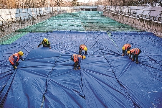 1月3日，房山區(qū)東風(fēng)街道，工人正在修復(fù)的河道內(nèi)給混凝土鋪設(shè)保溫布。