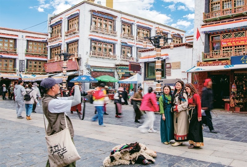 千年八廓街，見證民族團結(jié)。2021年7月，習近平總書記來到位于西藏拉薩老城區(qū)的八廓街，感慨地說：“千年八廓街，是我們各民族建起來的八廓街。各民族文化在這里交流交往交融，我們中華民族的大家庭在這里其樂融融。”圖為2023年6月13日，游客身著藏裝在八廓街拍照留念。 新華社記者 姜帆/攝