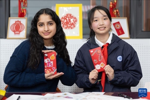 1月28日，美國(guó)馬斯卡廷中學(xué)學(xué)生（左）和復(fù)旦大學(xué)第二附屬學(xué)校學(xué)生展示互相送出的寫有寄語(yǔ)祝福的紅包。 新華社記者 王翔 攝