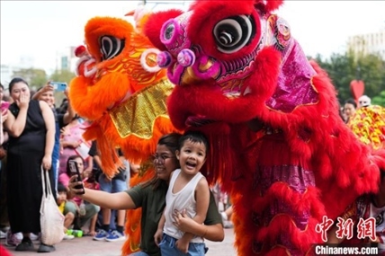 圖為舞獅表演吸引民眾合影。張興龍攝