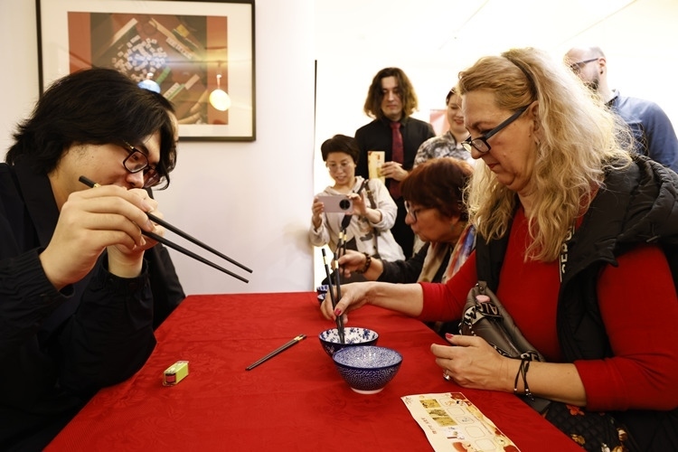 羅馬尼亞觀眾體驗(yàn)用筷子夾花生。中國(guó)文化中心供圖