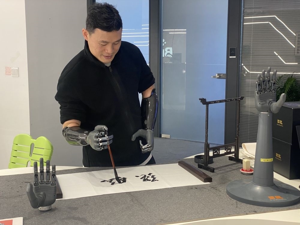 2024年3月29日，在浙江強(qiáng)腦科技有限公司展廳內(nèi)，失去雙手的產(chǎn)品體驗(yàn)官倪敏成依靠智能仿生手寫(xiě)毛筆字。新華社記者 魏一駿 攝