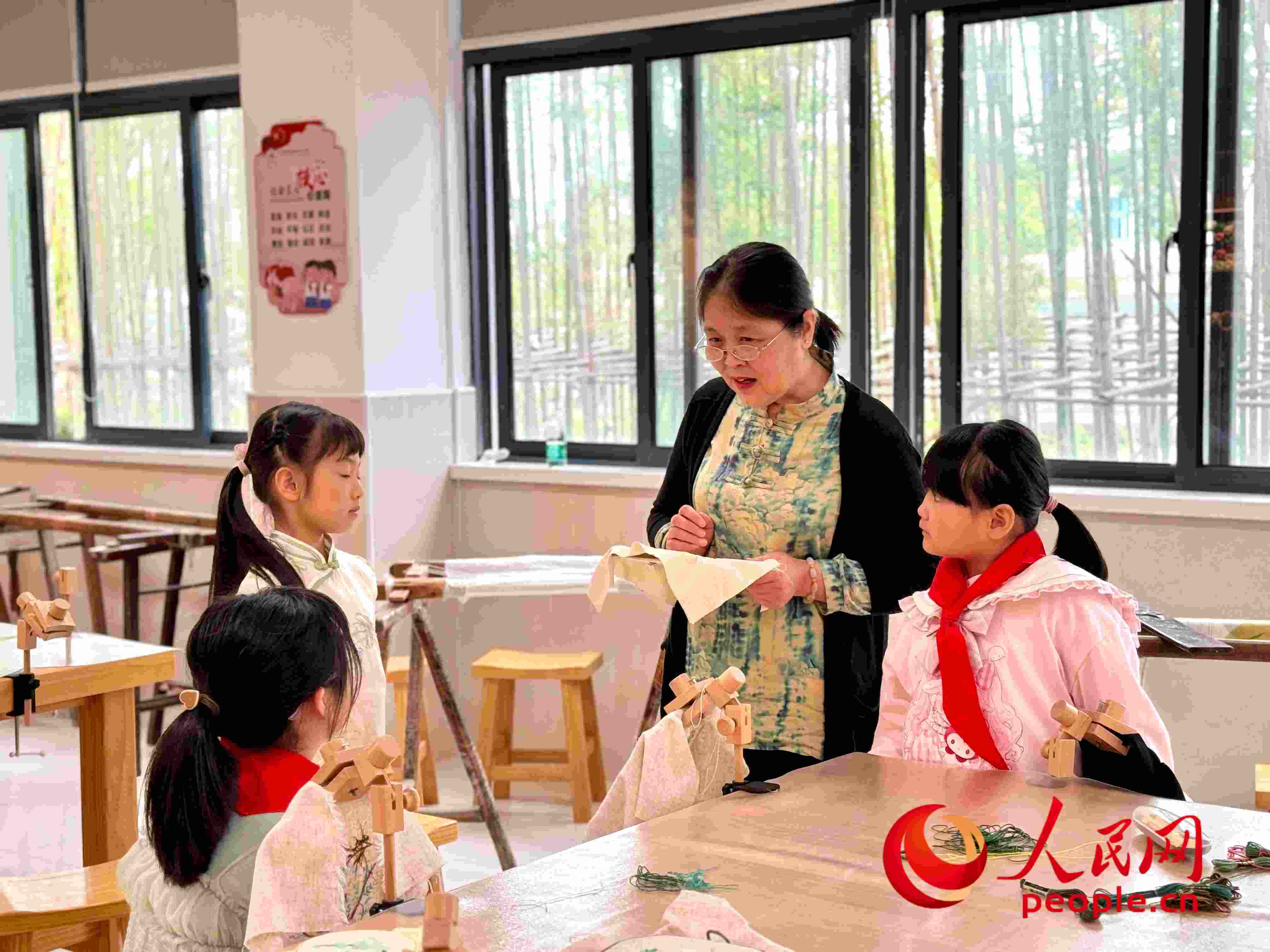 顧建珍（左三）在教孩子們刺繡知識。人民網(wǎng) 周靜圓攝