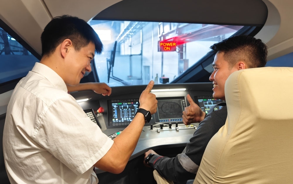 2023年8月25日，在印度尼西亞萬隆的雅萬高鐵德卡魯爾動車所內(nèi)，中國師傅穆振（左）向印尼火車司機塞蒂亞萬講解動車組出庫前的上電作業(yè)。新華社記者 徐欽 攝