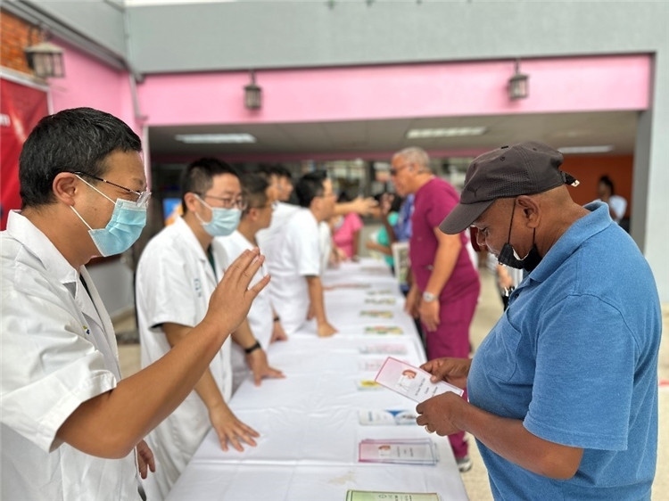 援圭醫(yī)療隊隊員們在啟動儀式上為當(dāng)?shù)孛癖姺职l(fā)宣傳手冊。中國援助圭亞那醫(yī)療隊供圖