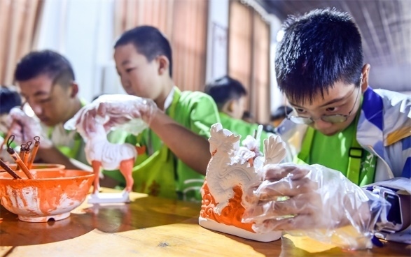 小朋友們在洛陽市孟津區(qū)朝陽鎮(zhèn)南石山村體驗唐三彩素胎施釉技藝。圖片來源：視覺中國