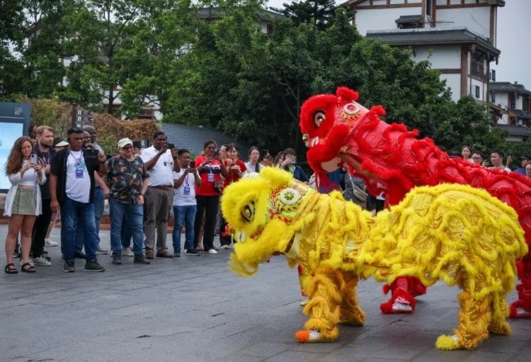 2024“一帶一路”媒體合作論壇聯(lián)合采訪調(diào)研行成員在樂(lè)山蘇稽古鎮(zhèn)觀看非遺舞獅表演。本報(bào)記者 伊霄攝