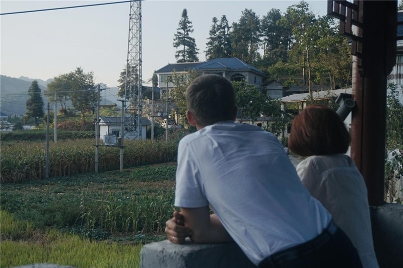 望得見山，看得見水，記得住鄉(xiāng)愁。每個人心中都有一個屬于自己的“花茂村”，在這方心田，走遍千山萬水，鄉(xiāng)音未改鬢毛衰。吉爾吉斯斯坦《比什凱克晚報》第一副總編輯妮娜·尼奇博洛娃與《中國與俄羅斯》雜志社社長奧列格·別列日內(nèi)赫攝在花茂村民居屋檐下并肩佇立，眺望山水，尋覓鄉(xiāng)愁。（李光裕攝）