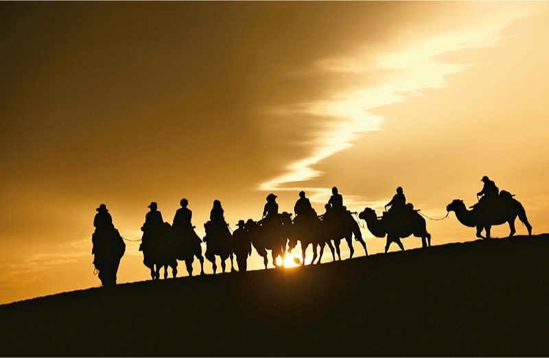 新時代以來，文化和旅游深度融合發(fā)展體制機制不斷健全，成功走出了一條獨具特色的中國旅游發(fā)展之路。圖為2024年9月1日清晨，游客在甘肅省敦煌市鳴沙山月牙泉景區(qū)乘騎駱駝，欣賞大漠風光，體驗絲路風情。 新華社發(fā) 張曉亮/攝