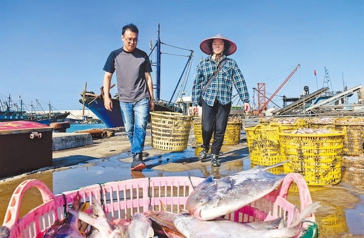 許小斌(左)和漁民一起搬運(yùn)海鮮。本報(bào)記者 付 文攝