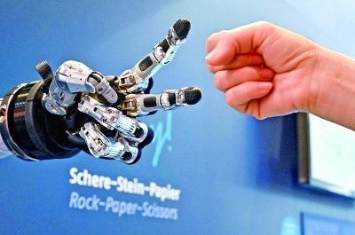 在德國漢諾威工博會上，參觀者與一款智能機器人進行“石頭剪子布”游戲。新華社發(fā)