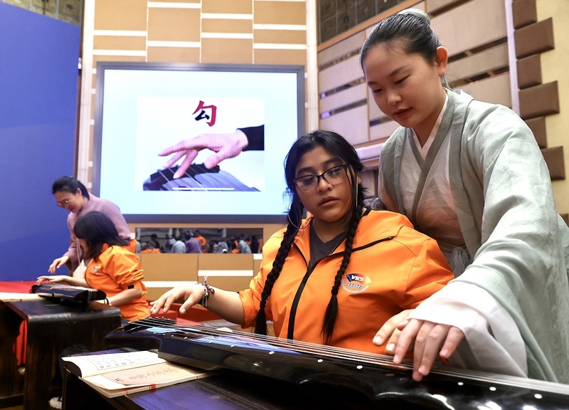 2024年3月20日，美國華盛頓州中學(xué)生代表團北京大學(xué)交流活動在北京大學(xué)英杰交流中心舉行。圖為來自華盛頓州的中學(xué)生體驗古琴。