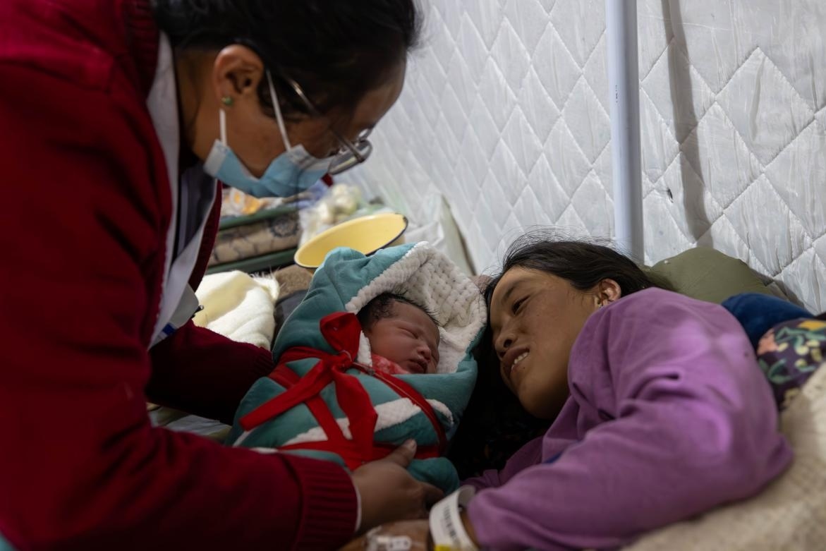 1月10日，定日縣中心醫(yī)院的婦產(chǎn)科醫(yī)生悉心照看一位母親和她懷里的新生兒。人民日報(bào)記者張武軍攝