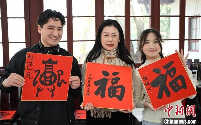 1月20日，外籍留學(xué)生和西泠印社社員李硯(中)展示各自創(chuàng)作的福貼。當(dāng)日，來自巴西、馬來西亞、加納、哈薩克斯坦的外籍留學(xué)生在浙江杭州西泠印社體驗福貼、春聯(lián)和篆刻，感受古老的中國傳統(tǒng)文化。中新社記者 王剛 攝