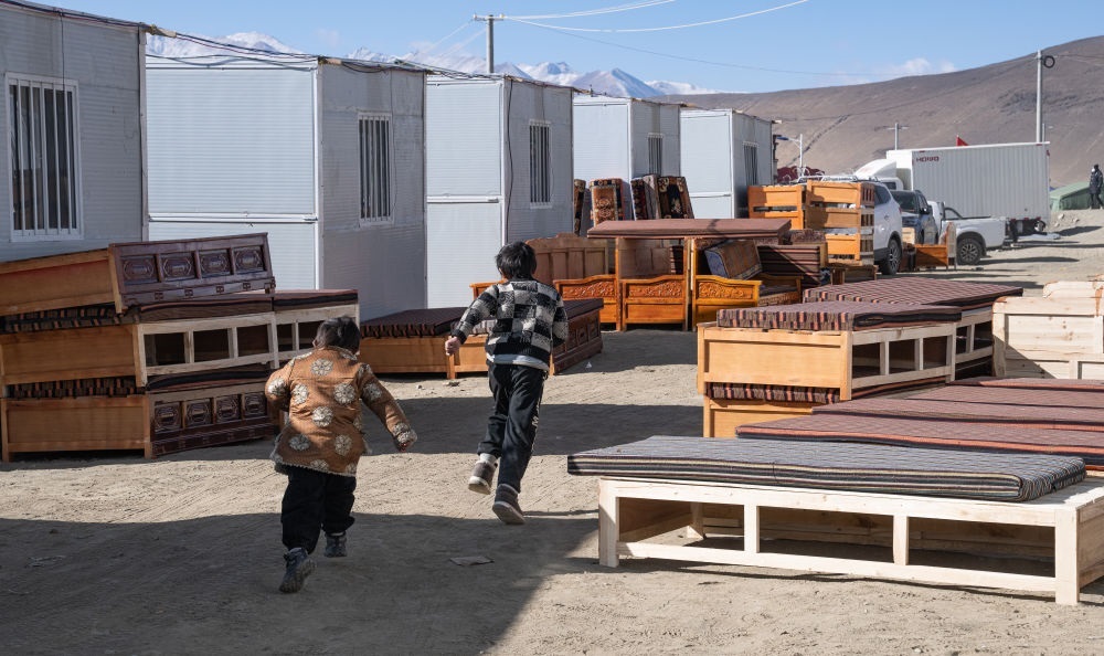 2025年1月13日，在定日縣嘎旦村，兩個(gè)孩子在剛運(yùn)來的兩排藏床間奔跑。新華社記者丁增尼達(dá) 攝