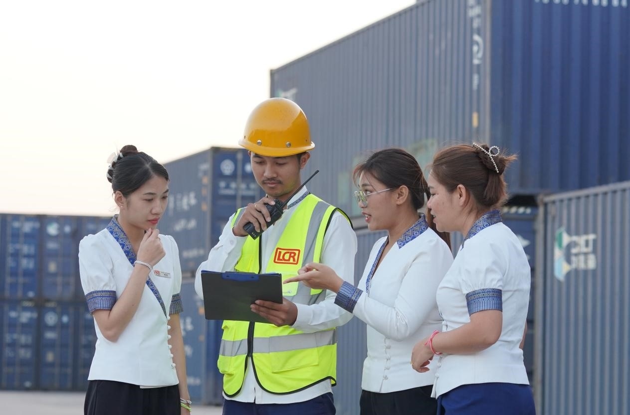 萬象南站貨運值班員陳尼啦（左一）與同事在一起討論工作。老中鐵路有限公司供圖