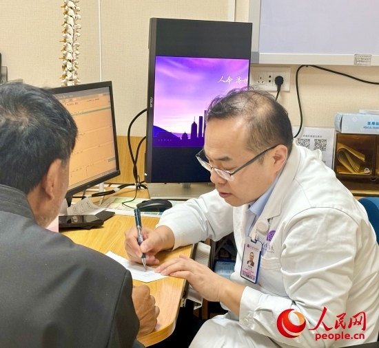 路桂軍接診時(shí)為患者寫下用藥提示。人民網(wǎng)記者 金慧慧攝