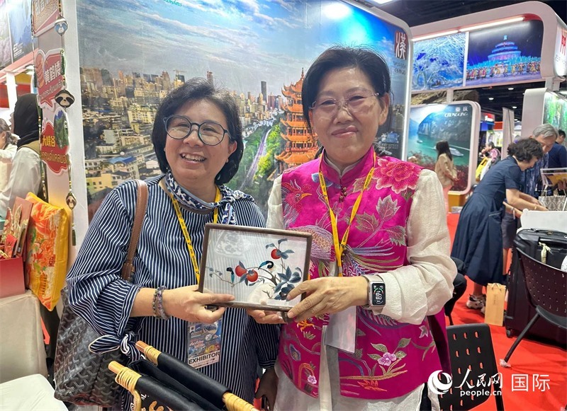 中國“大冶刺繡”傳承人劉小紅（右）參加泰國國際旅游展，向觀眾介紹中國非遺刺繡針法。人民網(wǎng)記者 簡承淵攝