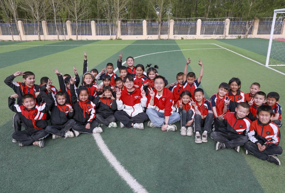 4月23日，在新疆克州阿圖什市哈拉峻鄉(xiāng)謝依特小學，支教教師王俊文（中左）、李軻凡（中右）和學生在一起。