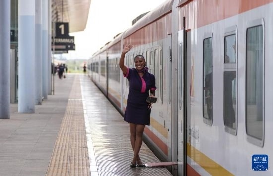 5月31日，在蒙內(nèi)鐵路內(nèi)羅畢站，一名乘務(wù)員在即將開往蒙巴薩的E2次列車旁等候乘客。新華社記者 李亞輝 攝